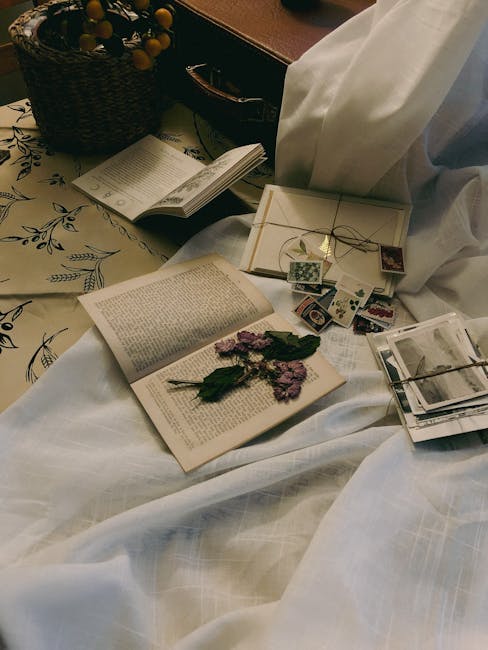 A nostalgic arrangement of books, letters, and dried flowers on fabric.